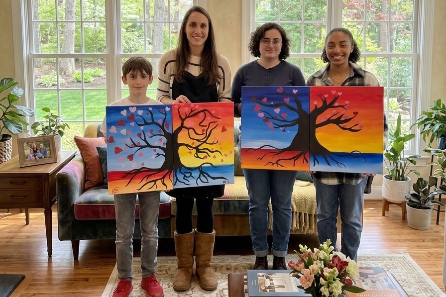Four guests holding pairs of colorful tree paintings that join together